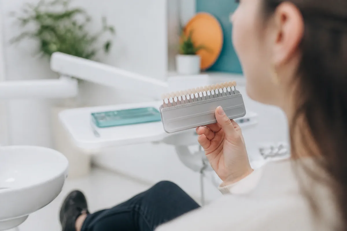 Patient examinant la teinte de ses dents devant un teintier professionnel